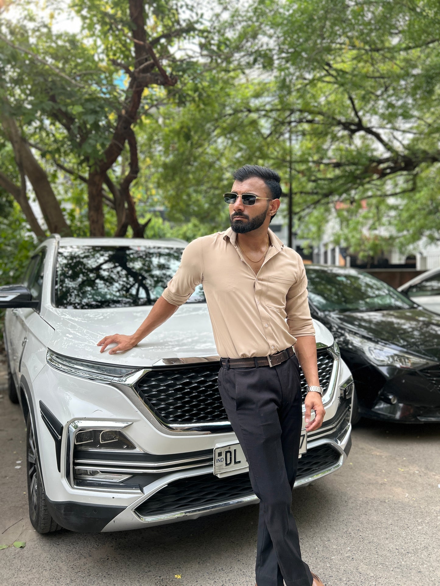 Man standing next to a white SUV in an urban setting with trees in the background