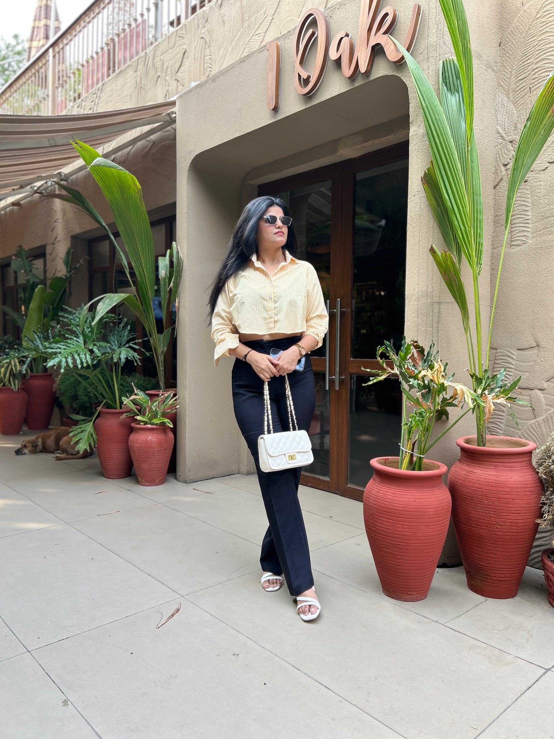 Woman standing in front of a building entrance with plants around